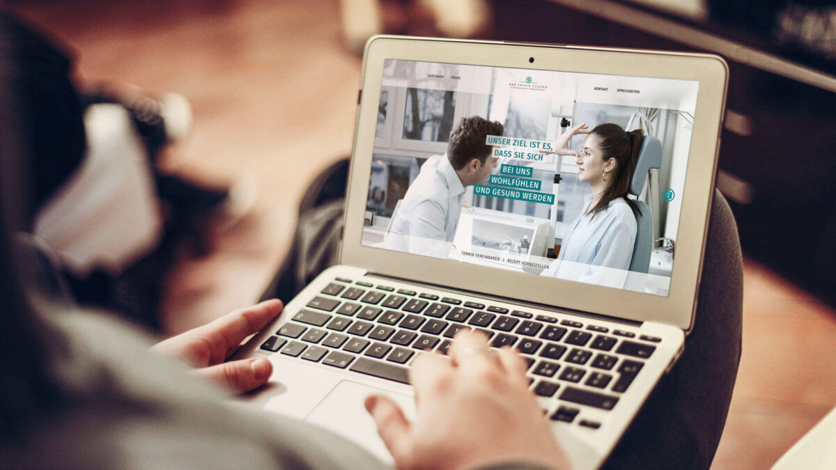 Eine Person hält einen Laptop auf dem Schoß, auf dem die Website HNO-Praxis Kudamm geöffnet ist. Auf der Startseite ist ein Bild mit einem Arzt und einer Patientin zu erkennen, die sich in einem Beratungstermin befinden, welches von dem Text „Unser Ziel ist es, dass Sie sich bei uns wohlfühlen und gesund werden.“ begleitet wird.
